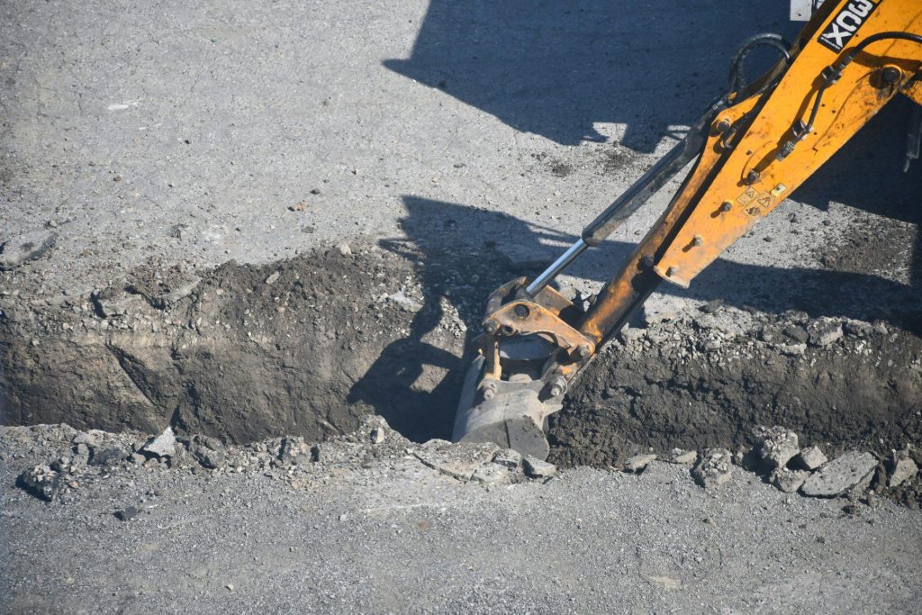 Excavator digging into pavement